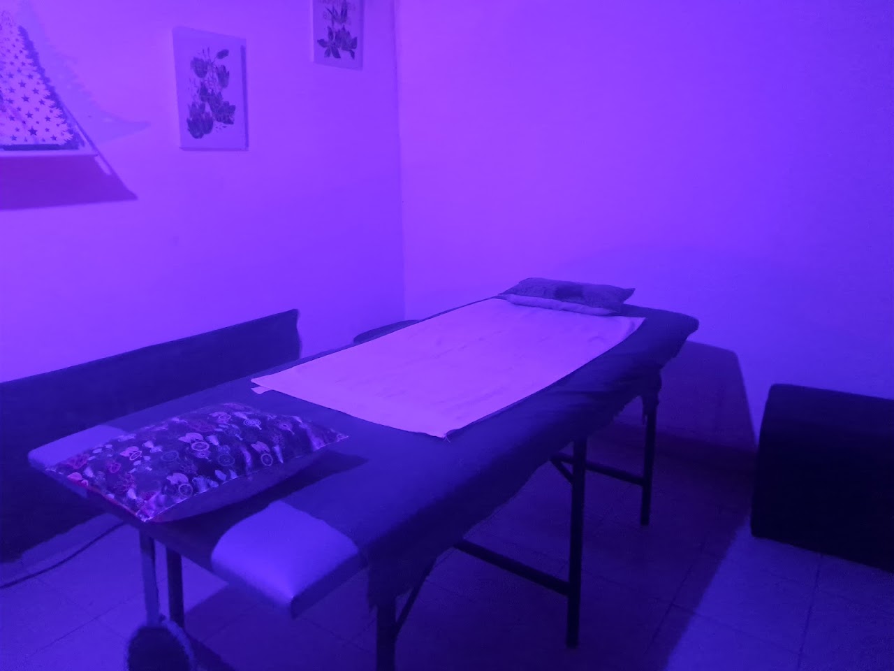 Gabinete de masajes ambientado con toallas blancas, iluminación tenue violeta y velas relajantes